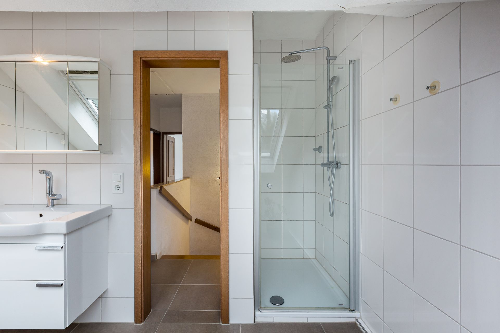 Modernes Badezimmer mit Waschbecken, Spiegelschrank und Dusche mit Glastür.