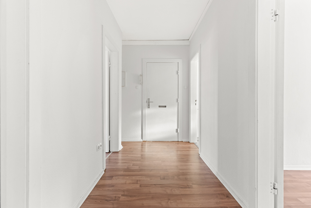 Heller Flur mit Holzboden, weißen Wänden und mehreren Türen in einer Wohnung.