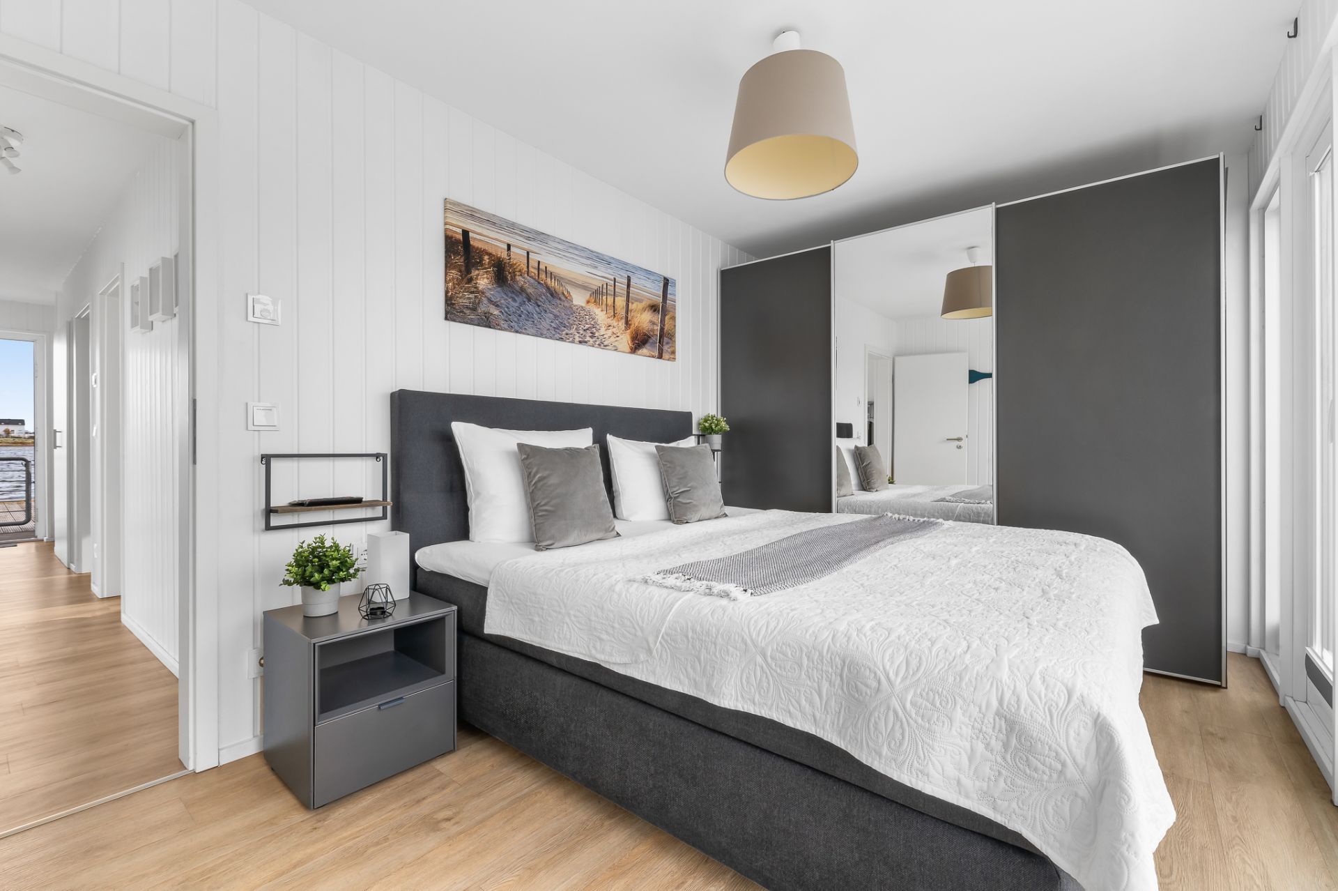 Modernes Schlafzimmer mit Doppelbett, Nachttisch, Schrank mit Spiegel und Bild an der Wand.