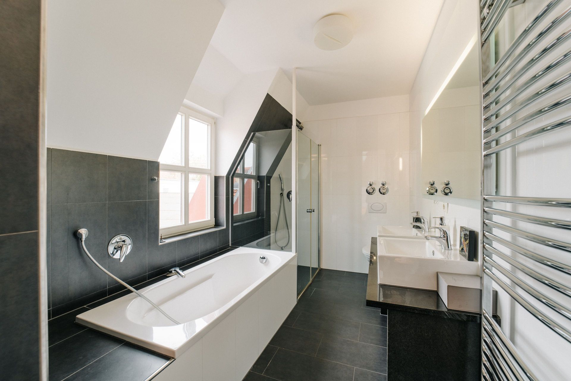 Modernes Badezimmer mit Badewanne, Dusche, Doppelwaschbecken und Handtuchheizung.