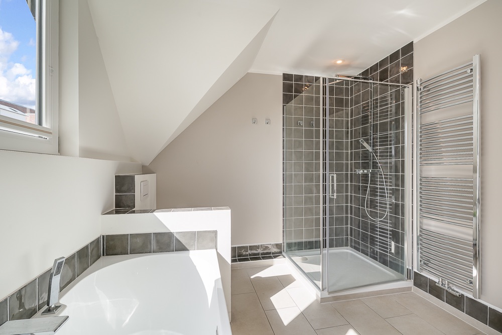 Modernes Badezimmer mit Badewanne, Dusche mit Glaswand und Handtuchheizung.