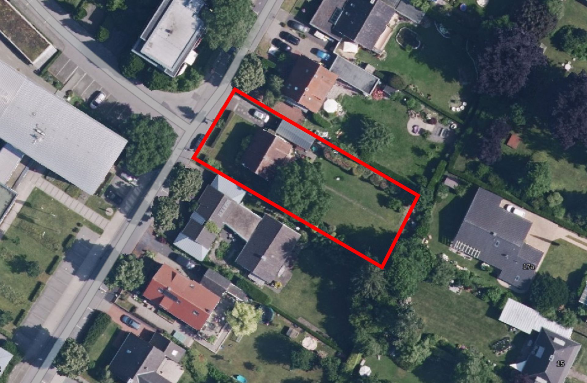 Luftbild eines Grundstücks mit Haus und Garten, rot umrandet inmitten weiterer Gebäude und Grünflächen.