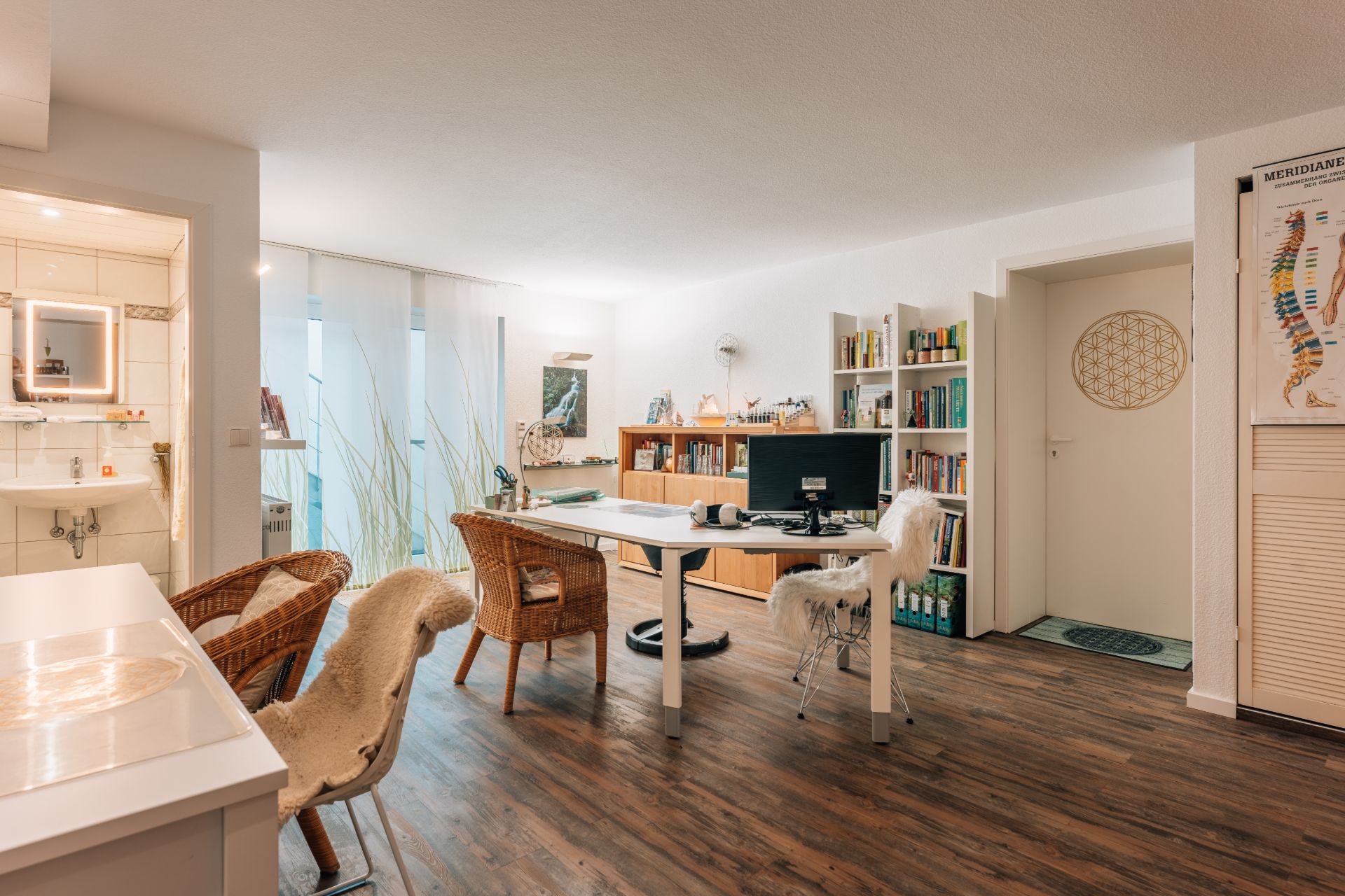 Helles Wohn- und Arbeitszimmer mit Schreibtisch, Regalen, Stühlen und Blick ins Bad.