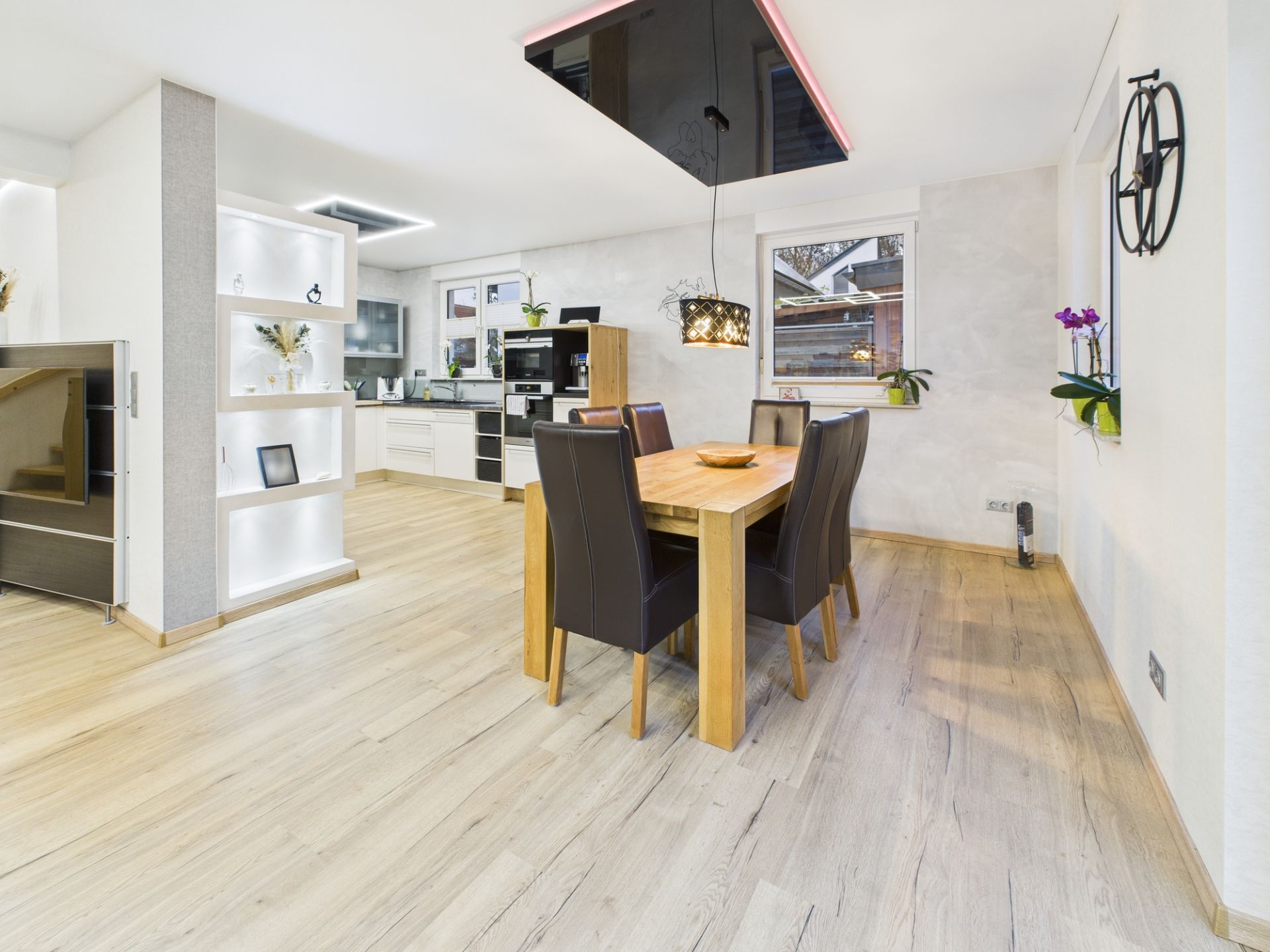 Moderne Wohnküche mit Holztisch, sechs Stühlen und hellem Boden.