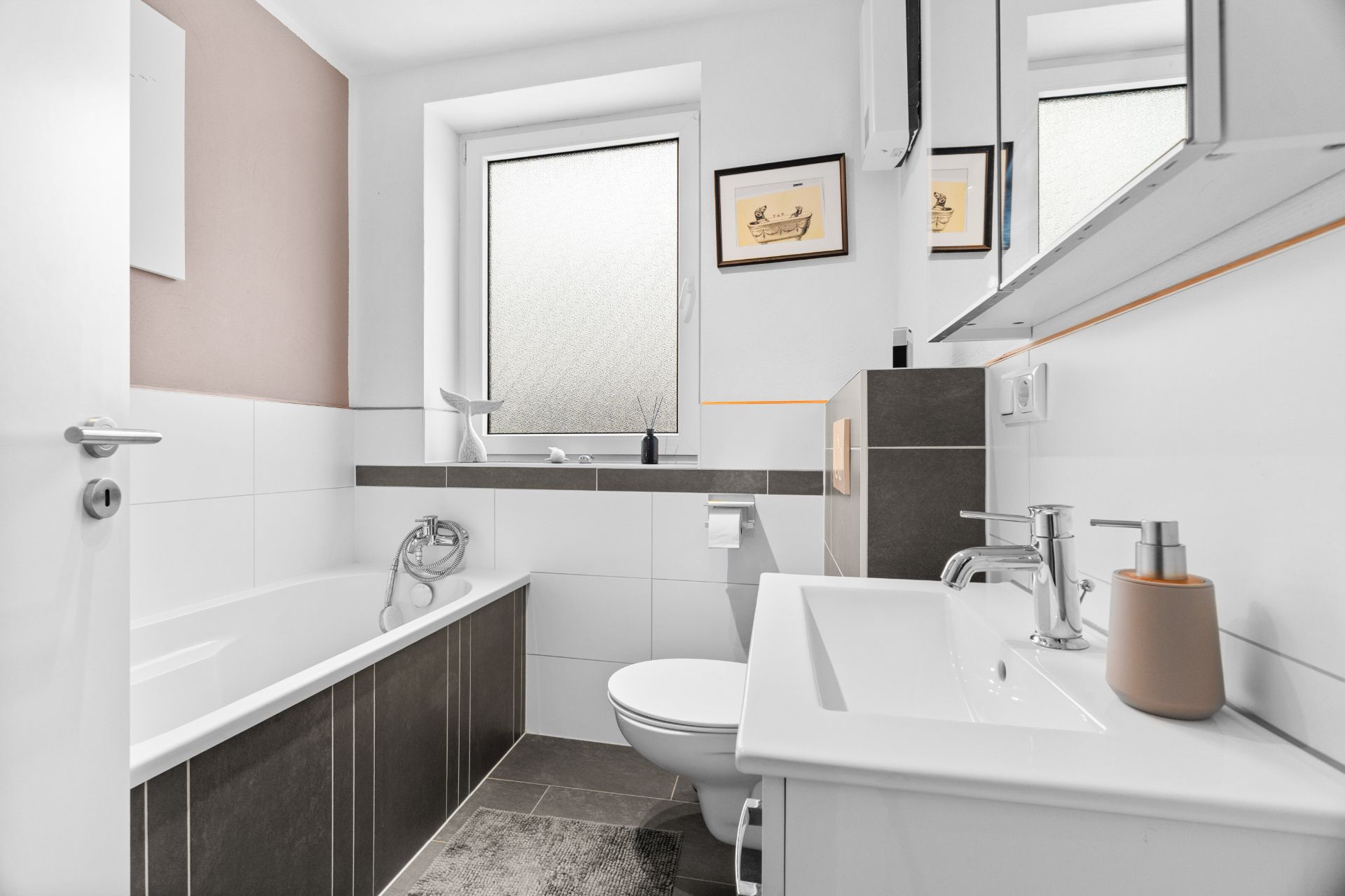 Modernes Badezimmer mit Badewanne, Waschbecken, Toilette und großem Fenster.