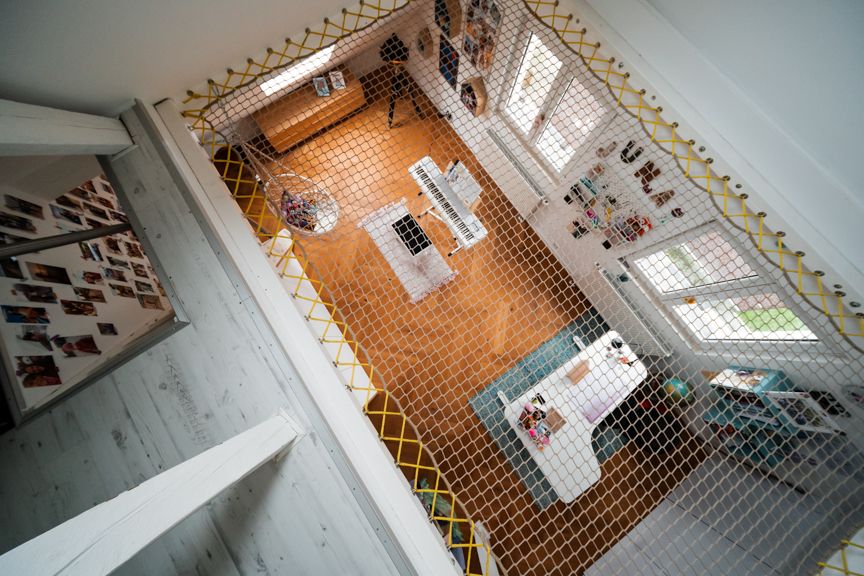 Blick von oben auf ein Wohnzimmer mit Netz, Schreibtisch, Sofa und Wandbildern.
