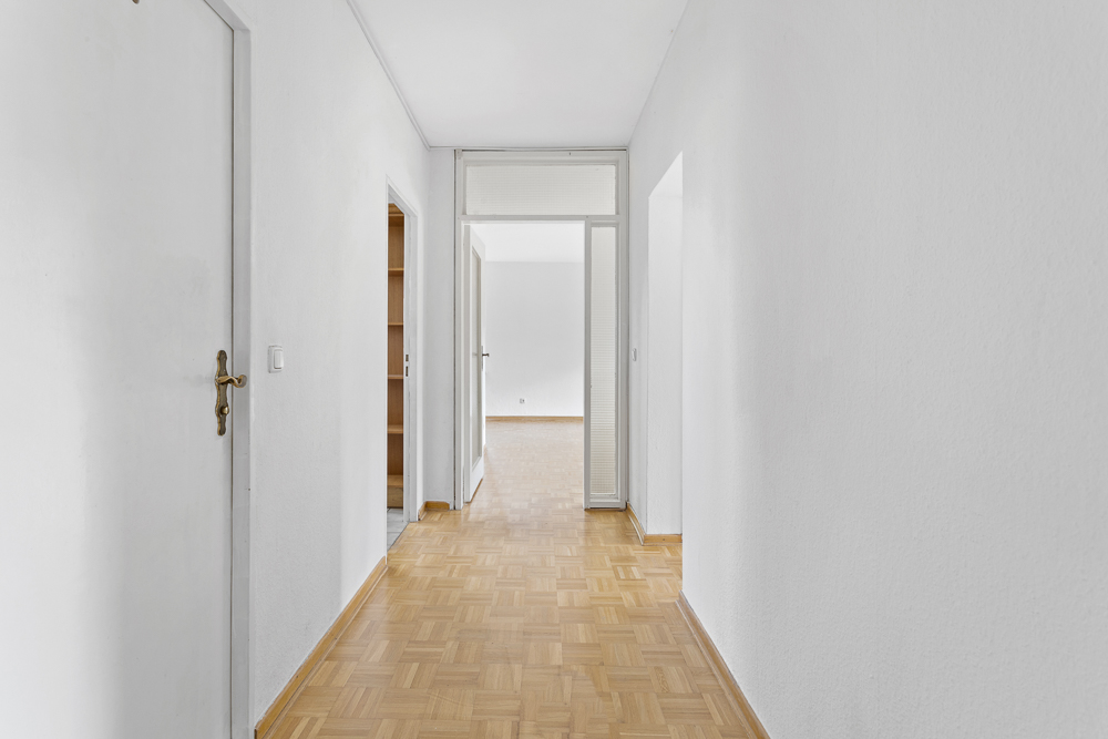 Heller Flur mit Parkettboden und weißen Wänden, Türen zu weiteren Zimmern sichtbar.