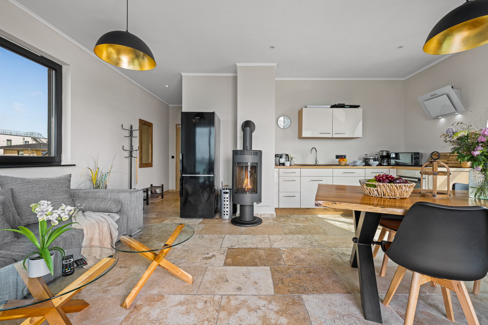 Helles Wohnzimmer mit Kamin, offener Küche, Esstisch und Sofa, moderne Einrichtung.