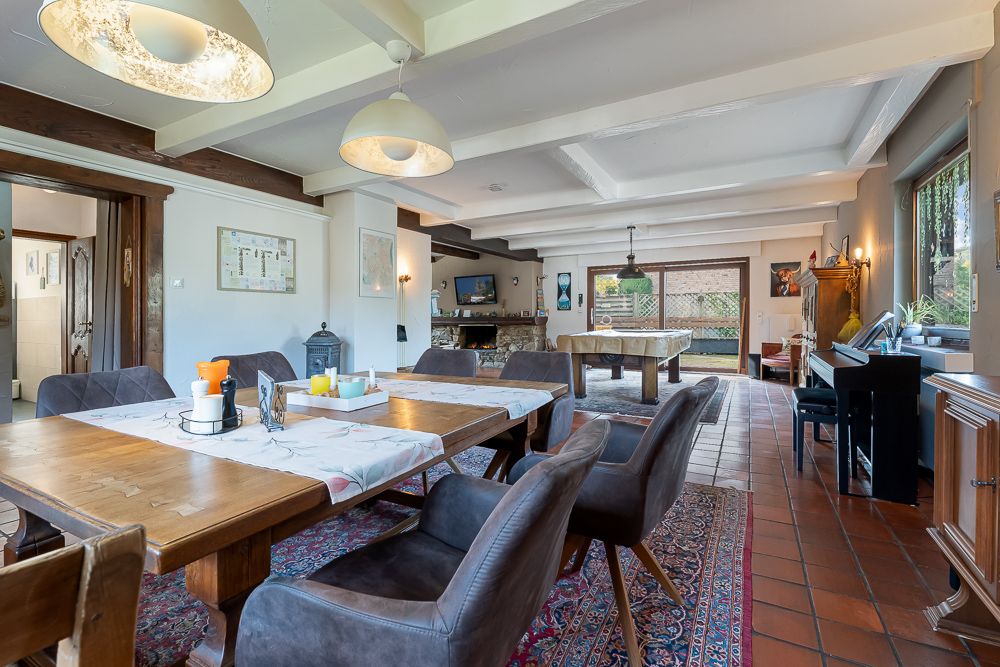 Helles Esszimmer mit Holztisch, grauen Stühlen, Teppich und großen Fenstern.