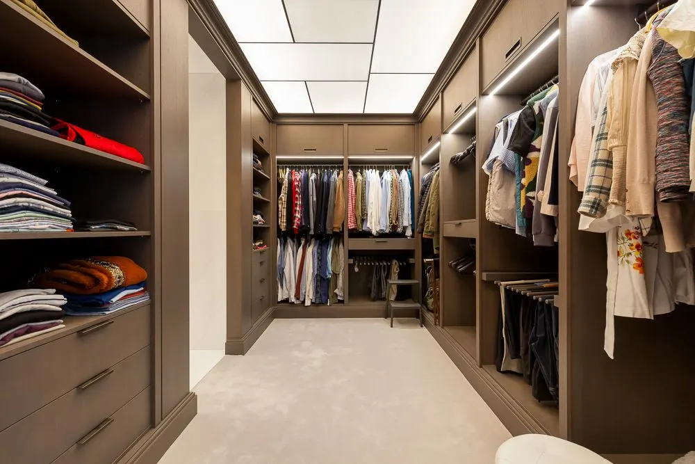 Moderner begehbarer Kleiderschrank mit Regalen, Hängestangen und ordentlich sortierter Kleidung.