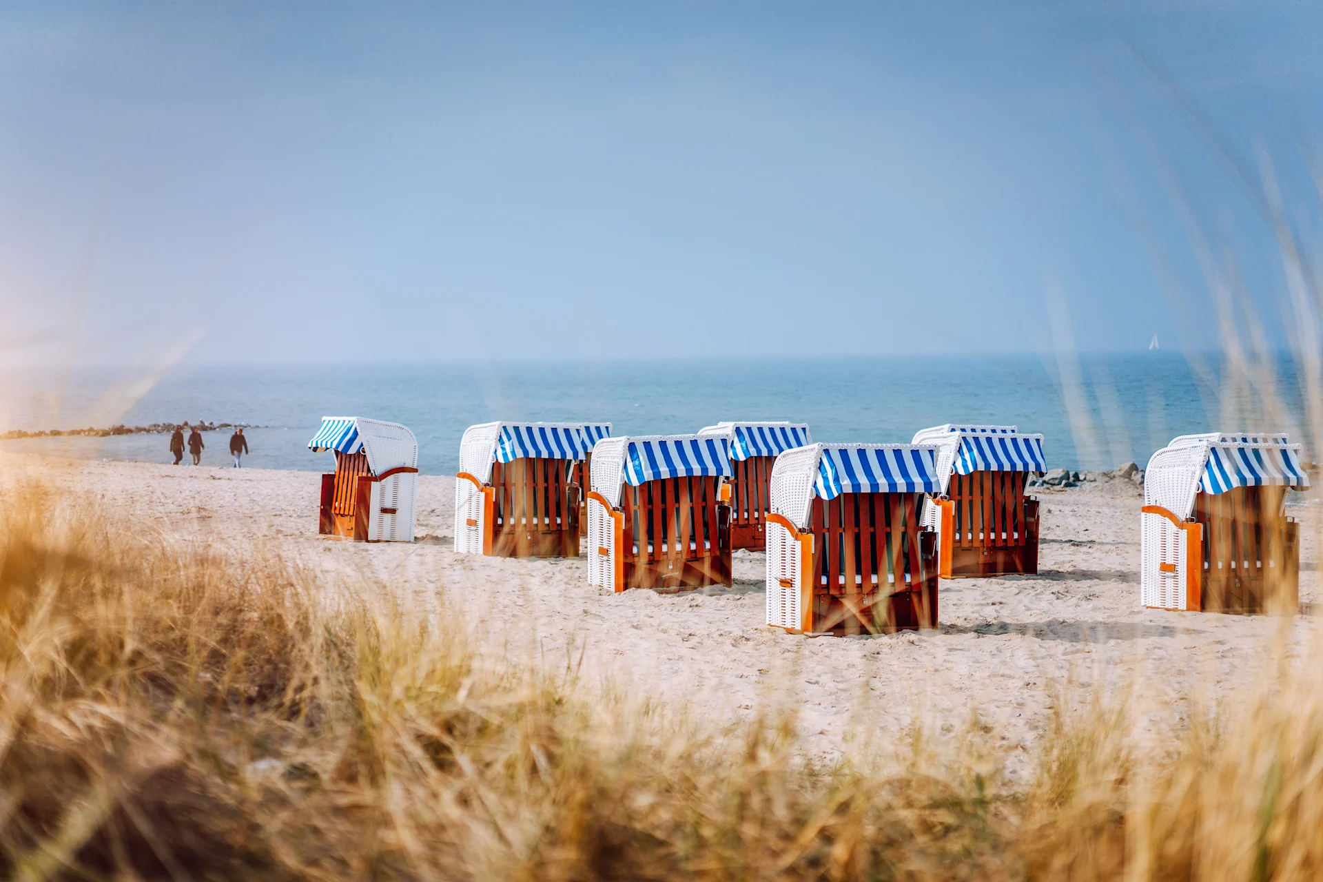 Luftbild von Küstenstadt mit Sandstrand, Meer und vielen Häusern im Grünen.