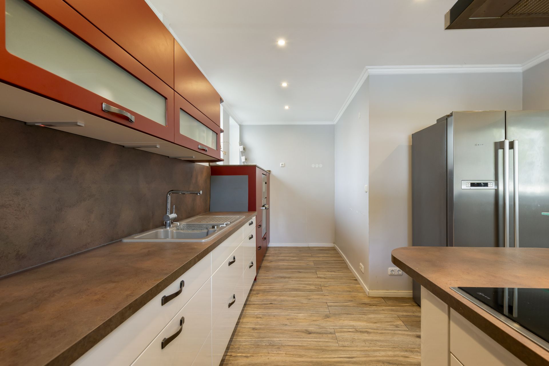 Moderne Küche mit brauner Arbeitsplatte, Spüle, Herd und großem Kühlschrank.