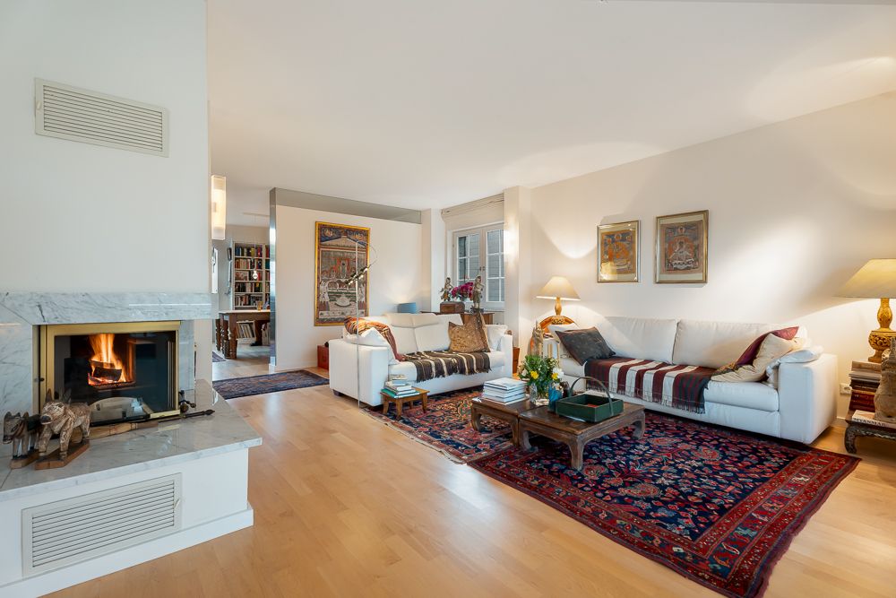 Helles Wohnzimmer mit Kamin, zwei weißen Sofas, Teppich und Kaffeetisch auf Holzboden.