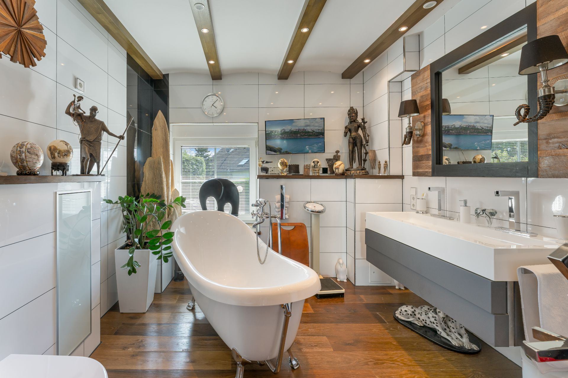 Modernes Badezimmer mit freistehender Badewanne, Doppelwaschbecken und Dekoration auf Holzfußboden.