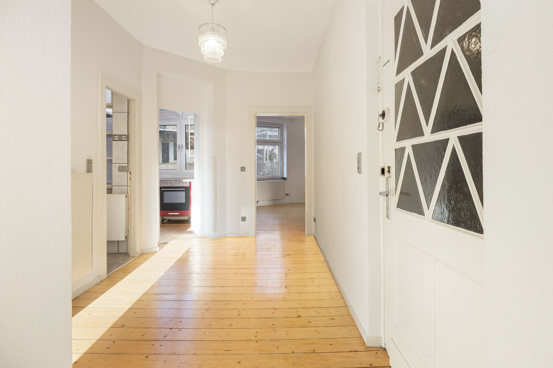 Heller Flur mit Holzboden, Türen zur Küche und zu einem weiteren Zimmer.