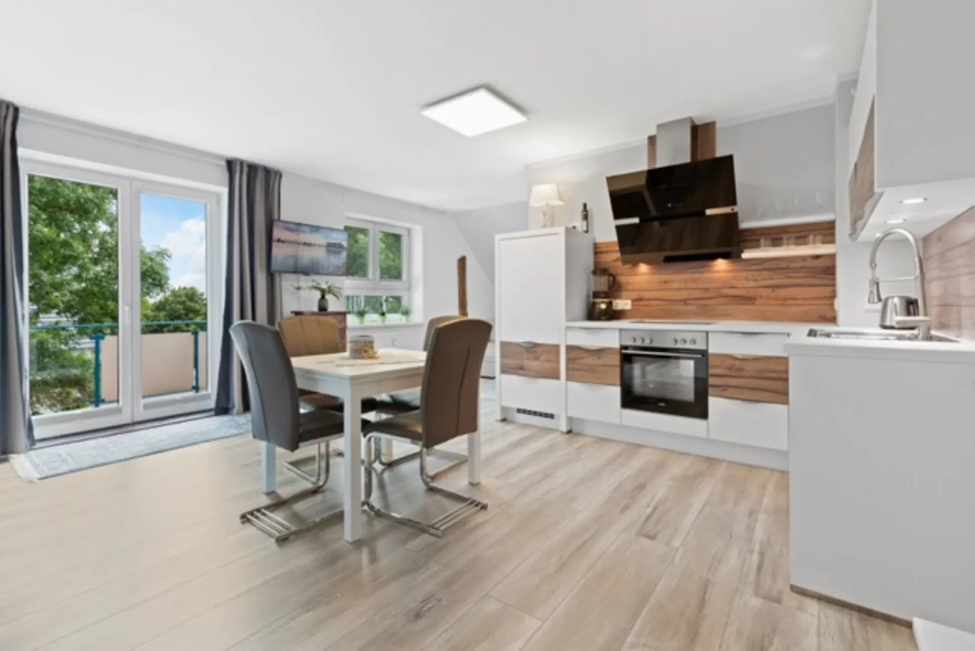 Moderne Küche mit Esstisch, vier Stühlen und großem Fenster mit Zugang zum Balkon.