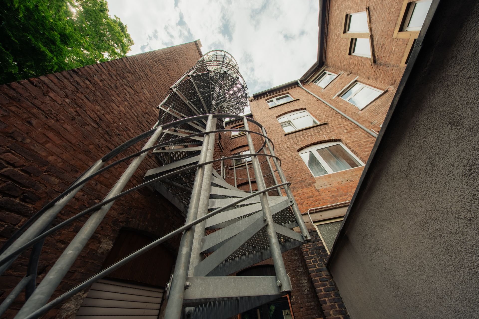 Metallwendeltreppe an der Außenseite eines Backsteingebäudes, Blick nach oben.