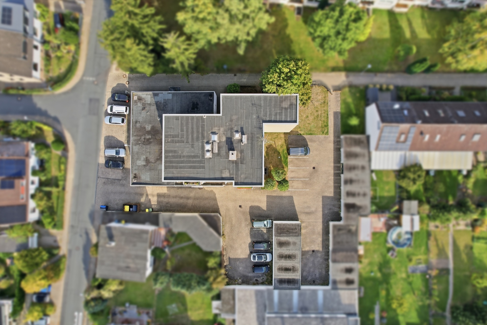 Luftaufnahme eines Wohnhauses mit Parkplätzen und umliegendem Garten.