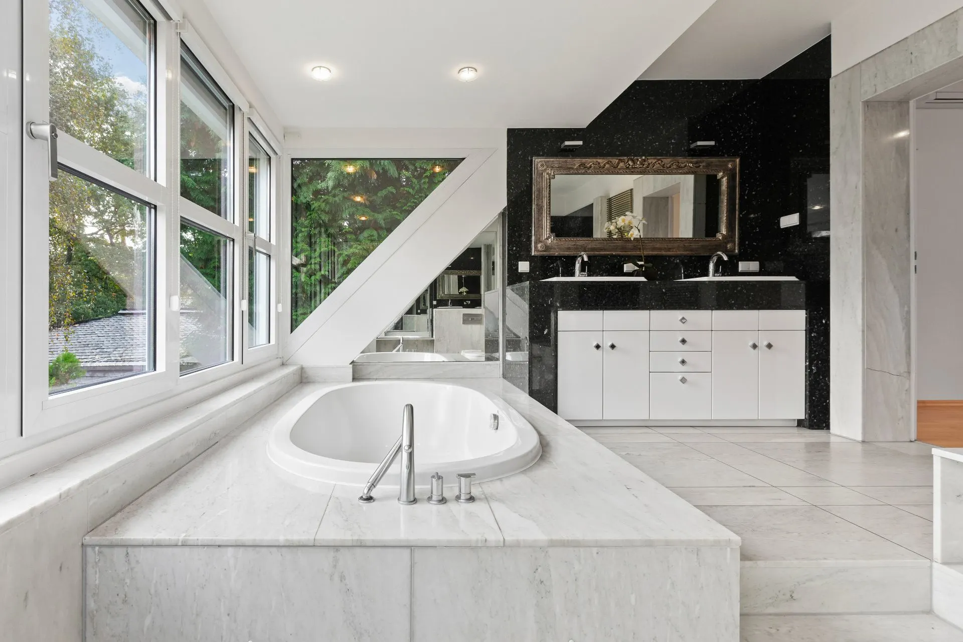 Modernes Badezimmer mit großer Badewanne, Doppelwaschbecken und großen Fenstern.