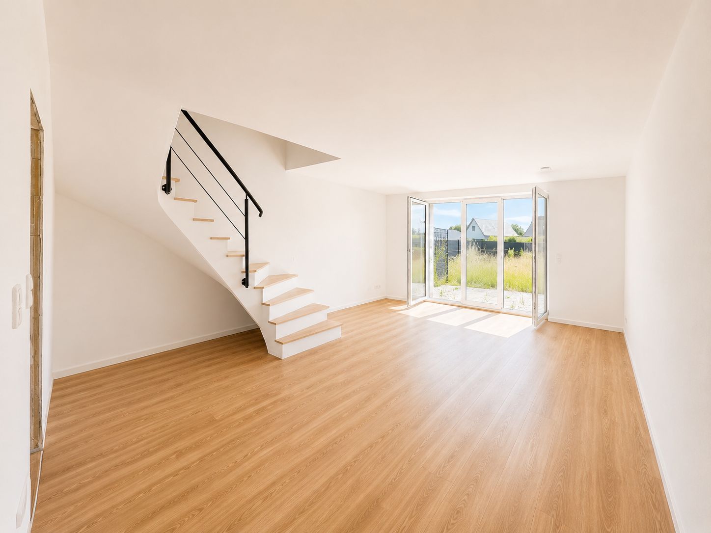Helles Wohnzimmer mit Holzfußboden, moderner Treppe und großen Glasfenstern zum Garten.