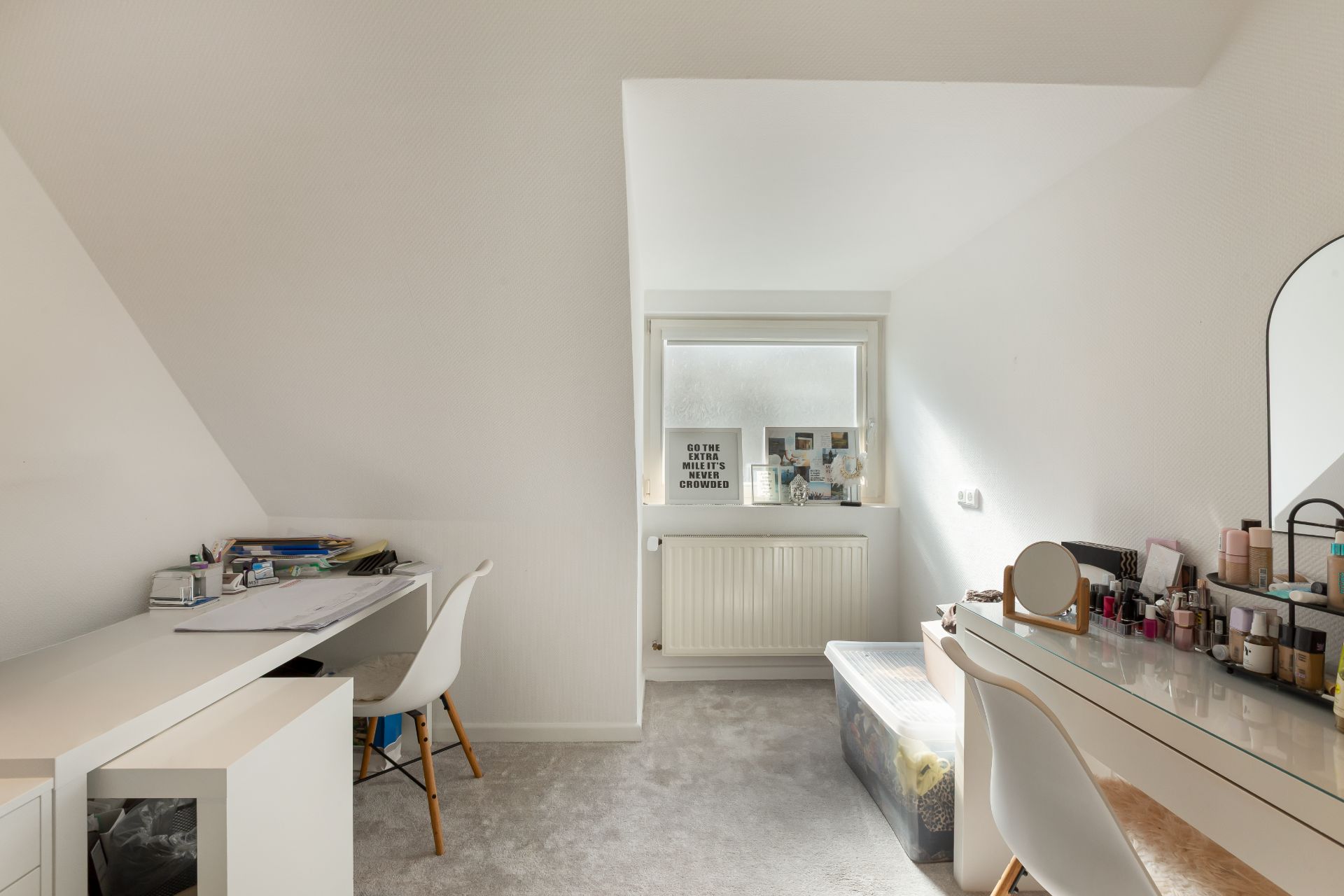 Helles Zimmer mit Schreibtisch links, Schminktisch rechts und Fenster am Ende des Raumes.