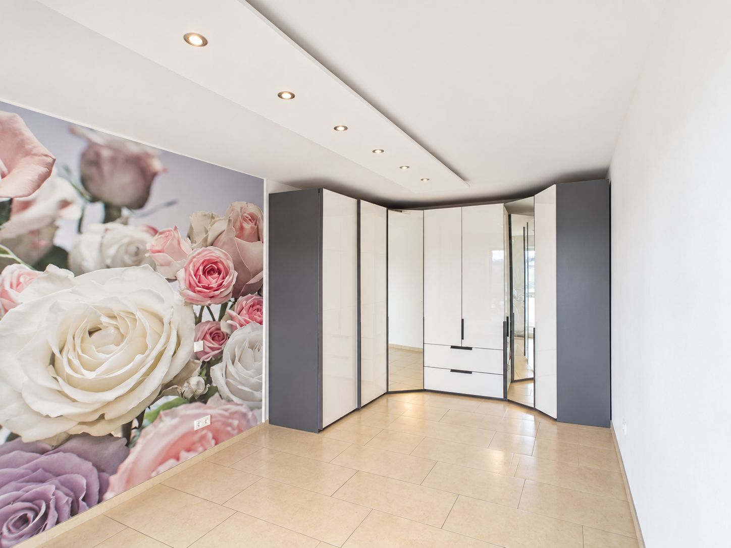 Leeres Zimmer mit großem Einbauschrank und Blumenfototapete an einer Wand.