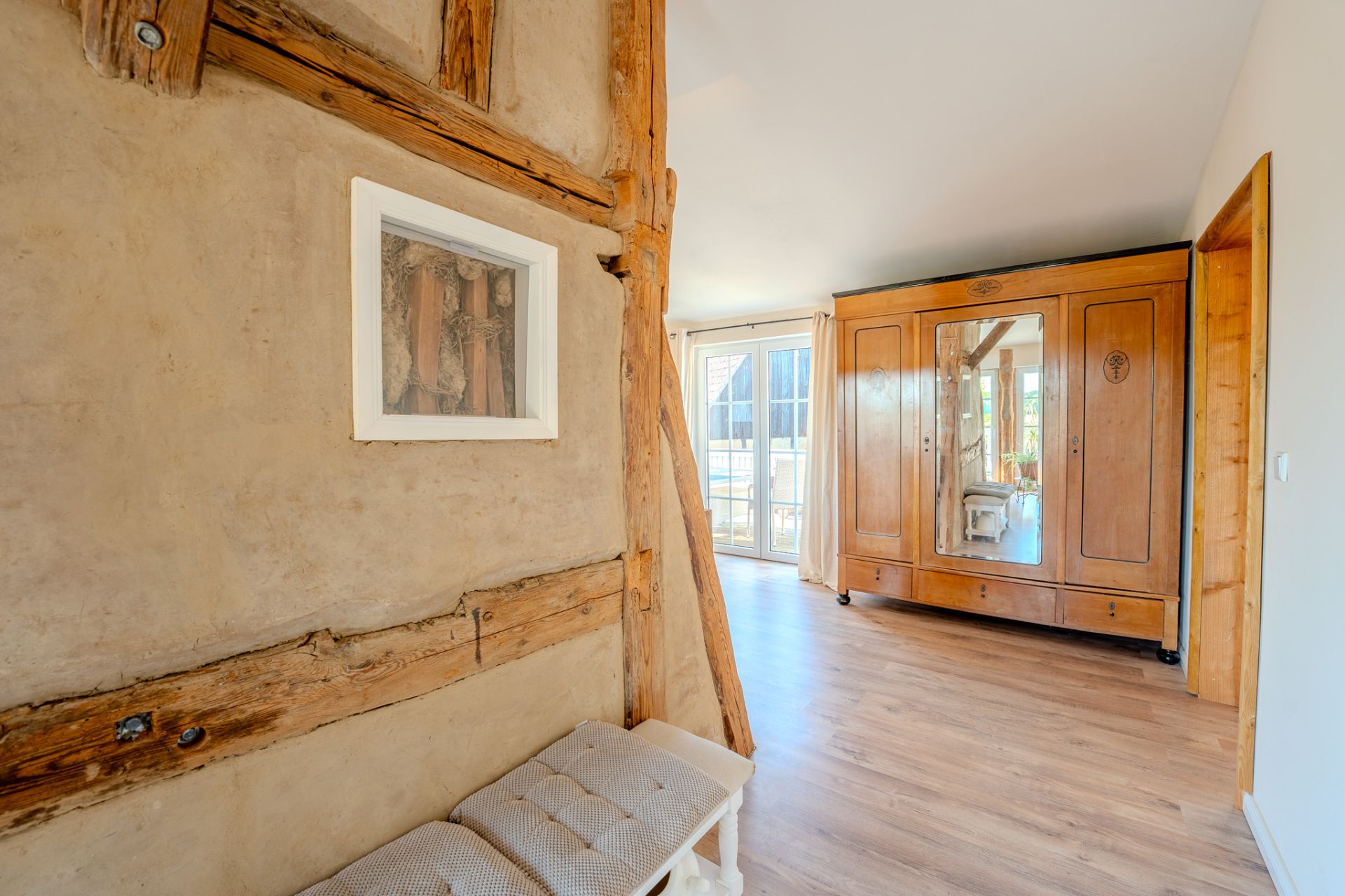 Heller Raum mit Holzschrank, Holzboden und sichtbaren Holzbalken an der Wand.