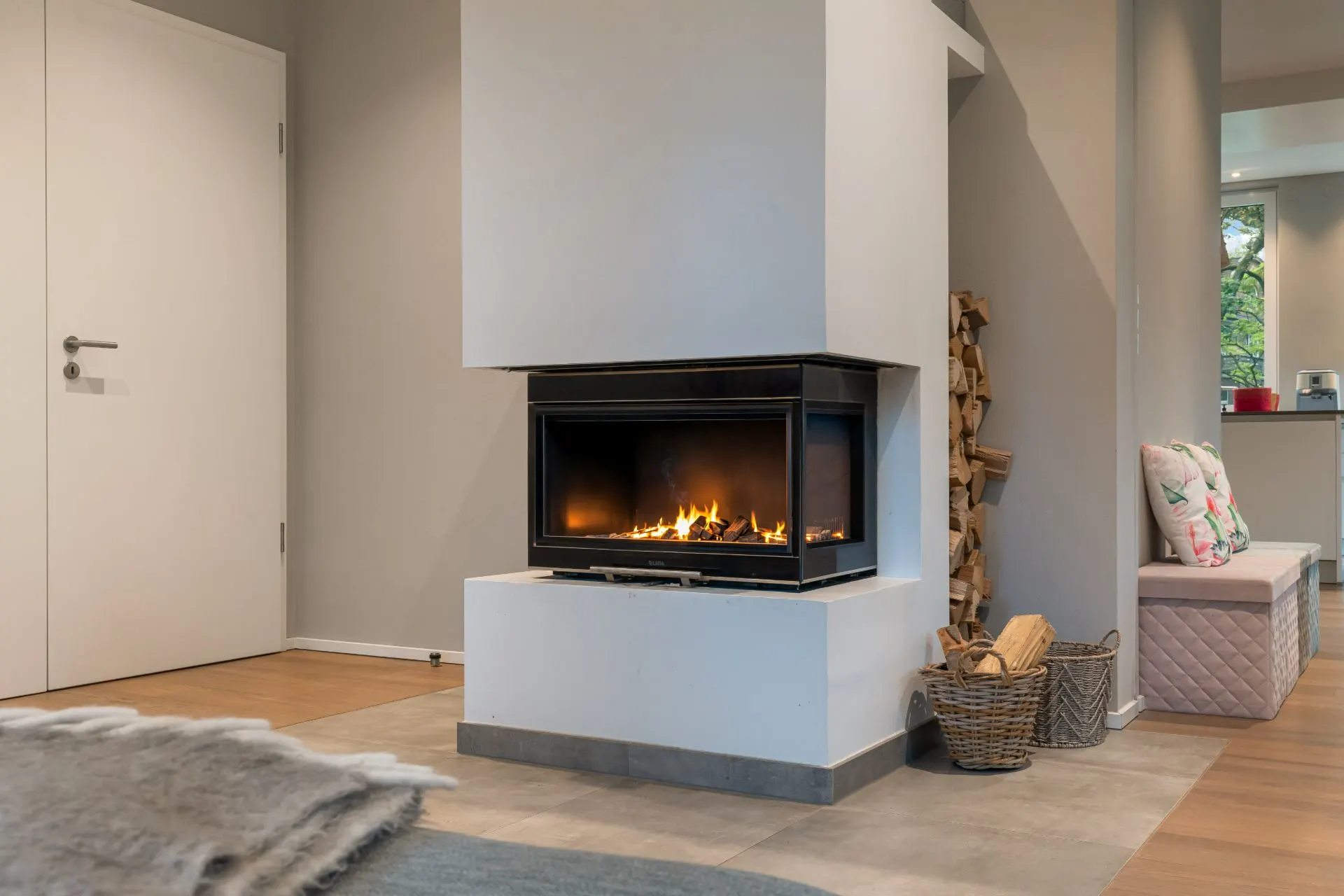 Modernes Wohnzimmer mit Kamin, Holzkorb und Sitzbank mit Kissen.