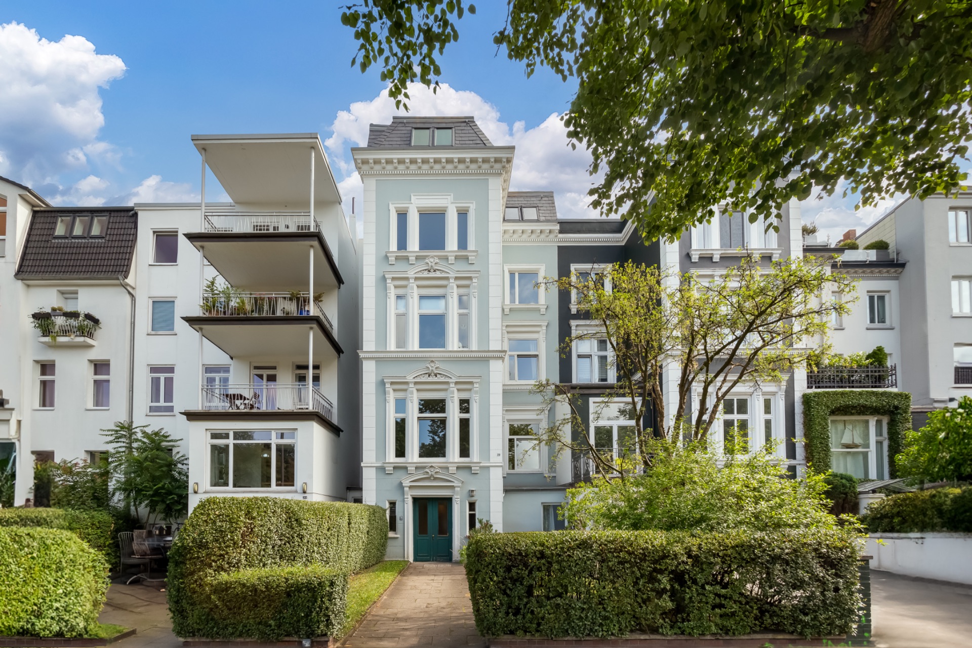 Mehrstöckiges Wohngebäude mit klassischen Fassadendetails und begrüntem Vorgarten.