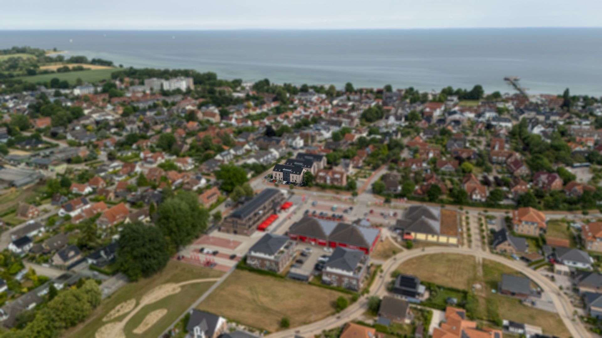 Verschwommene Luftaufnahme einer Wohngegend nahe dem Meer mit vielen Häusern und Straßen.