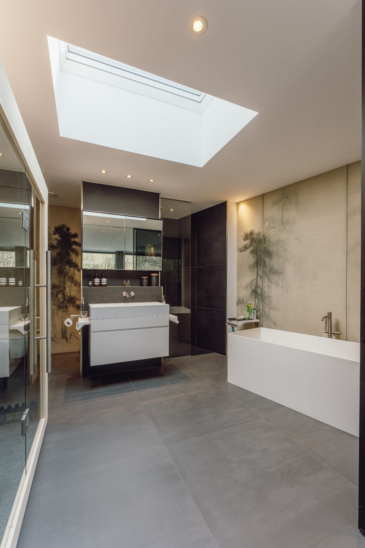 Modernes Badezimmer mit Badewanne, großem Spiegel, Doppelwaschbecken und Oberlicht.