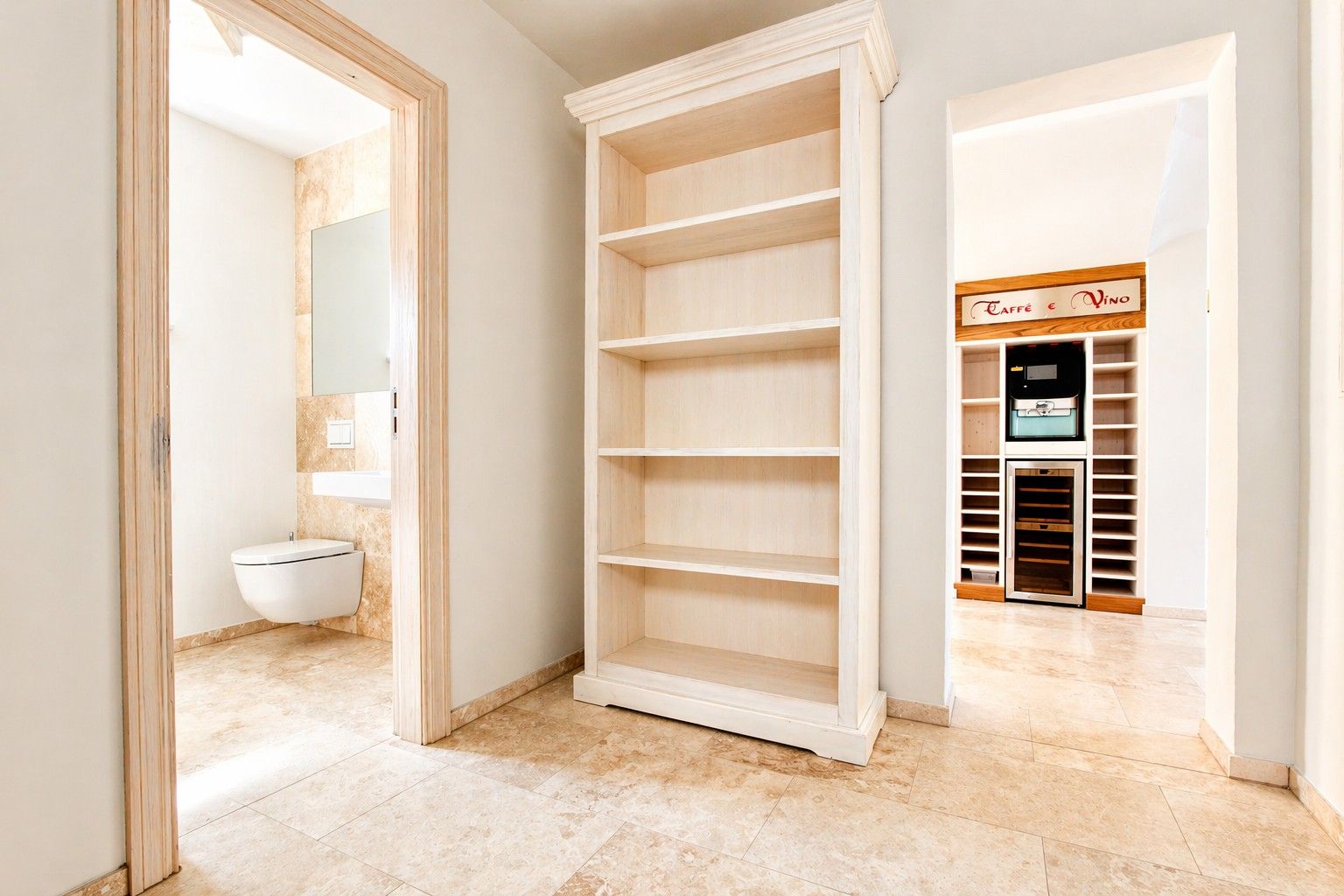 Flur mit Regal, Blick ins Bad mit WC und in einen Raum mit Regalen und Weinkühlschrank.