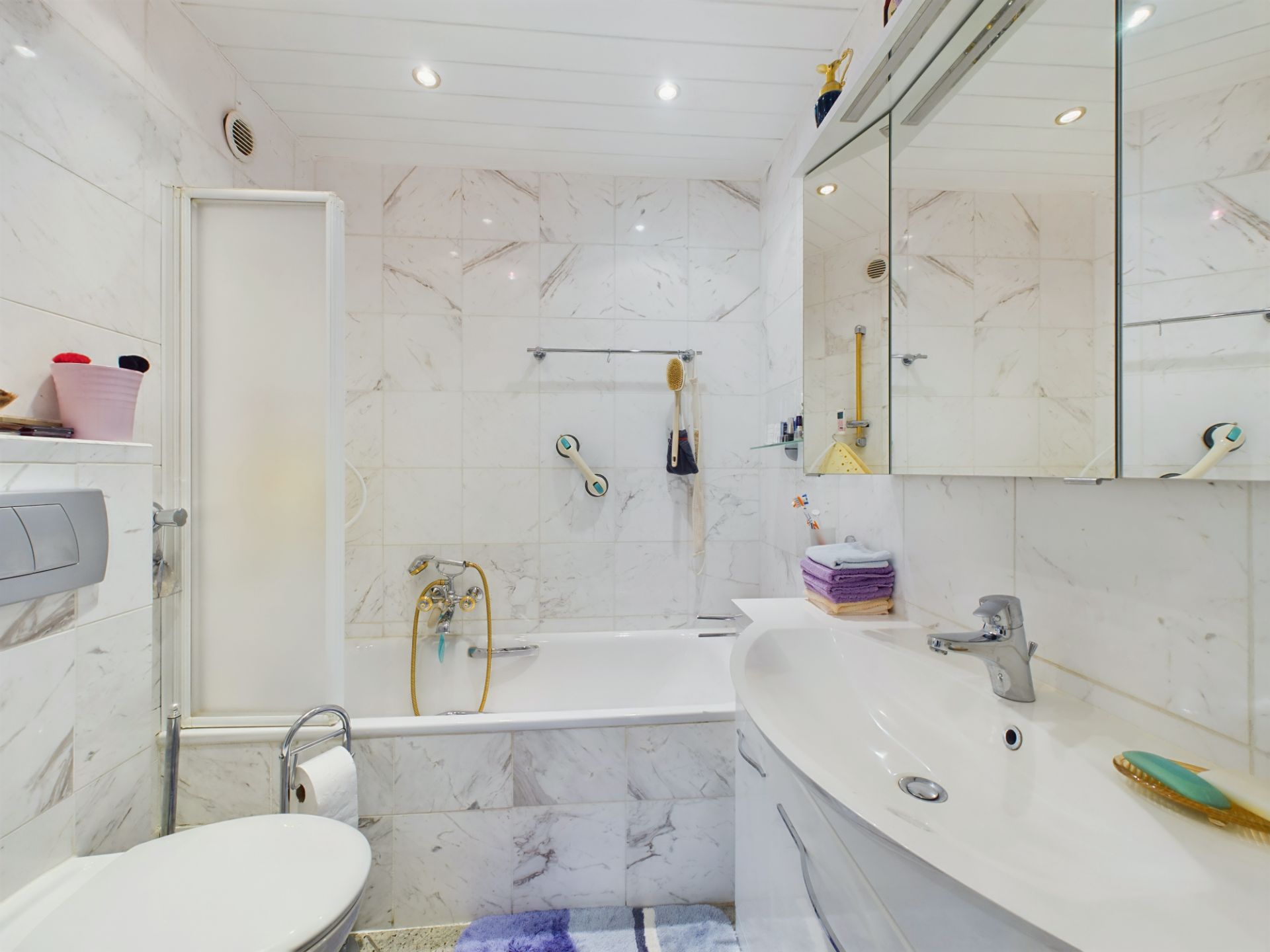 Modernes Badezimmer mit Badewanne, Spiegel, Waschbecken und weißen Fliesen.