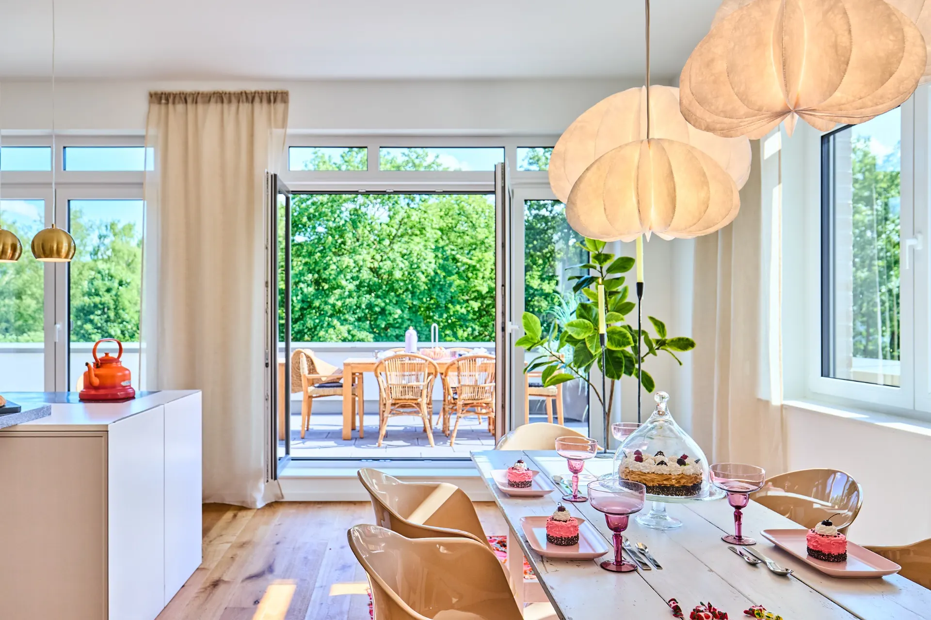 Essbereich mit gedecktem Tisch, großen Fenstern und Zugang zu einer Terrasse mit Sitzmöbeln.