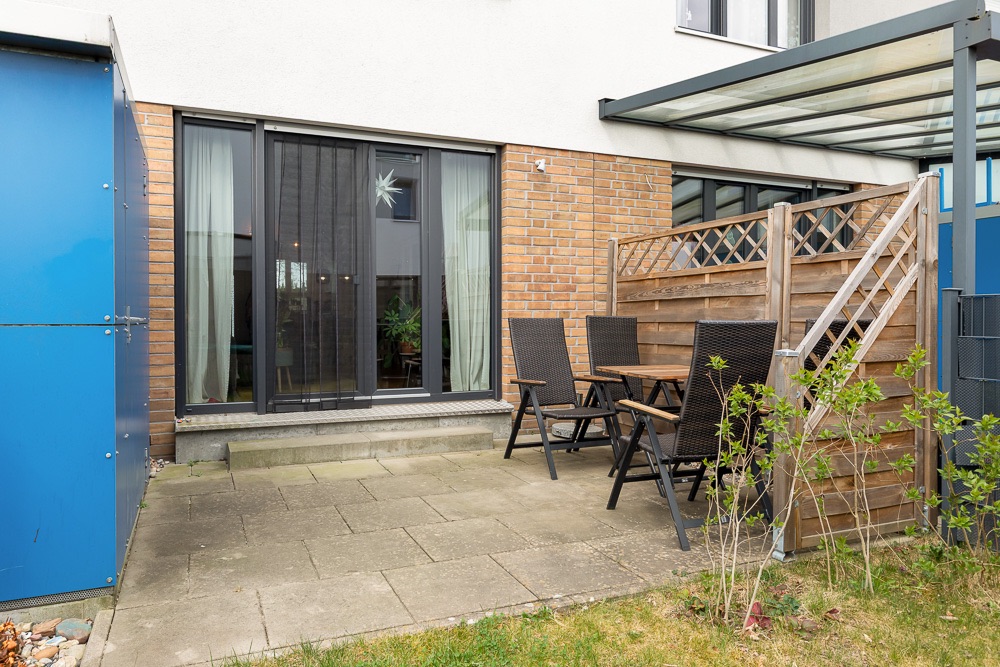 Kleine Terrasse mit Sitzgruppe, Holzzaun und direktem Zugang zum Wohnbereich.