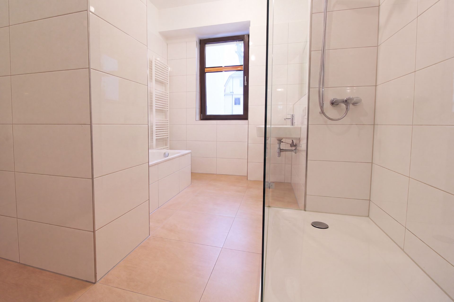 Modernes Badezimmer mit Dusche, Badewanne, Fenster und Handtuchheizkörper.
