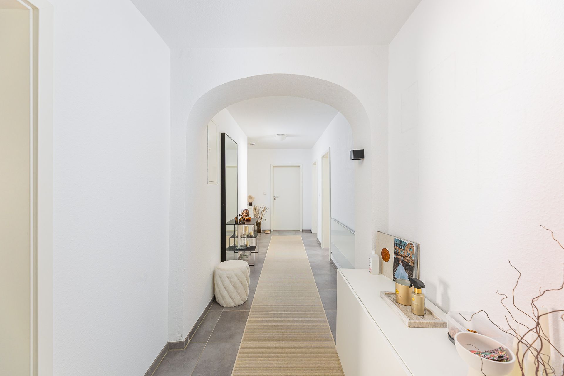 Heller Flur mit Dekoration, Spiegel, Kommode und Teppichläufer in einer Wohnung.