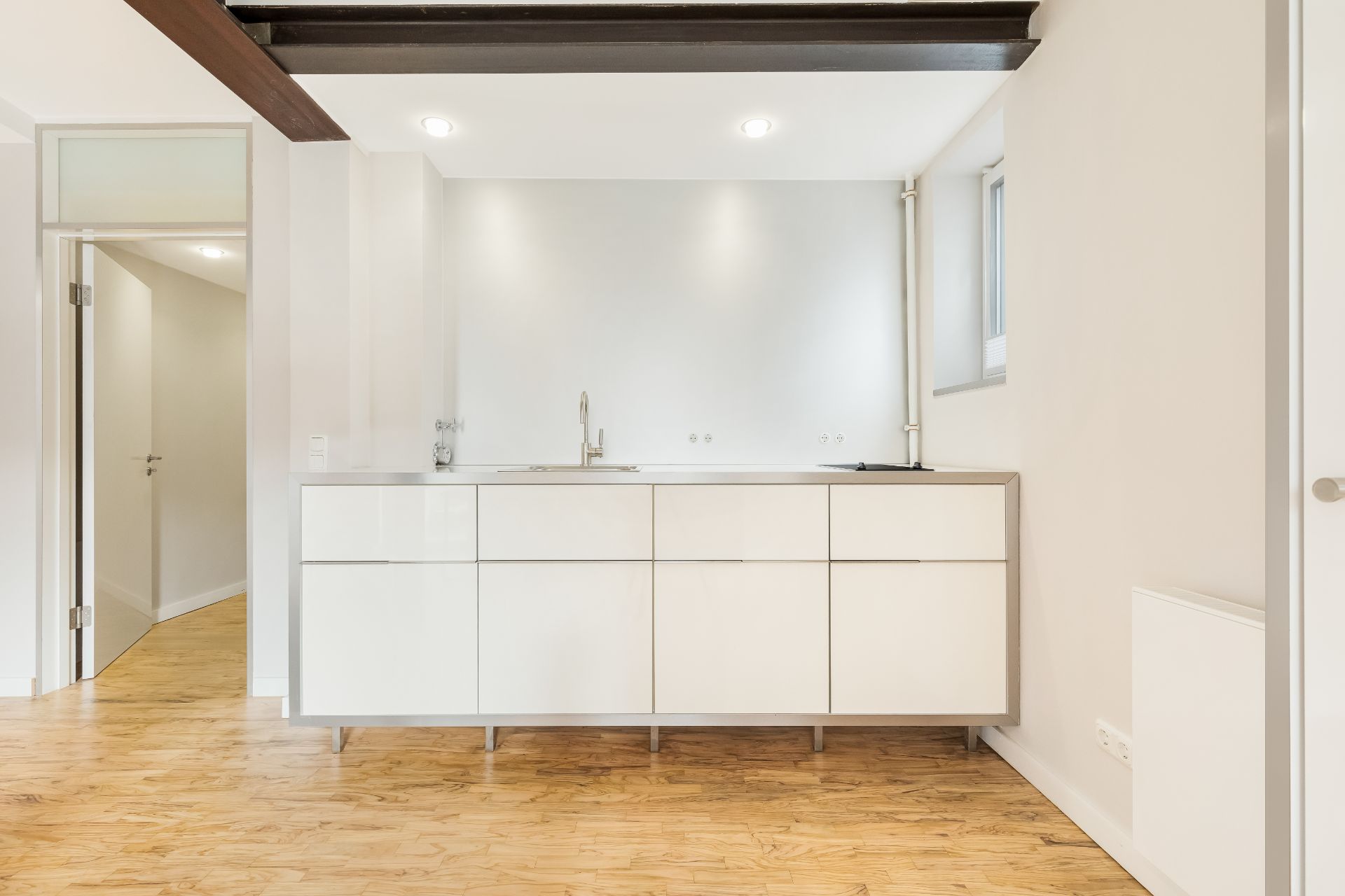 Moderne, minimalistische Einbauküche mit weißen Schränken und Holzfußboden.
