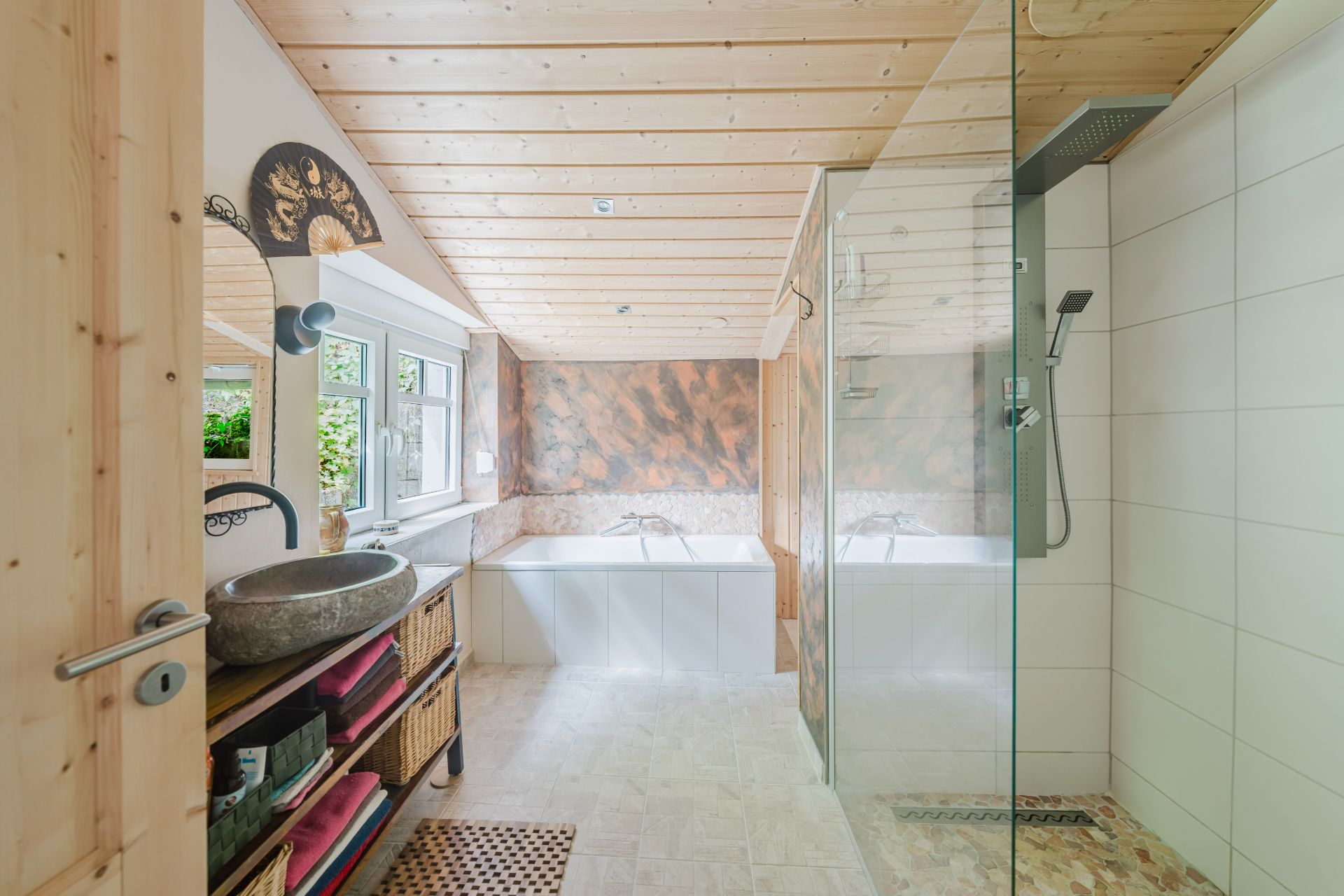 Modernes Badezimmer mit Holzdecke, Dusche, Badewanne und Waschbecken am Fenster.