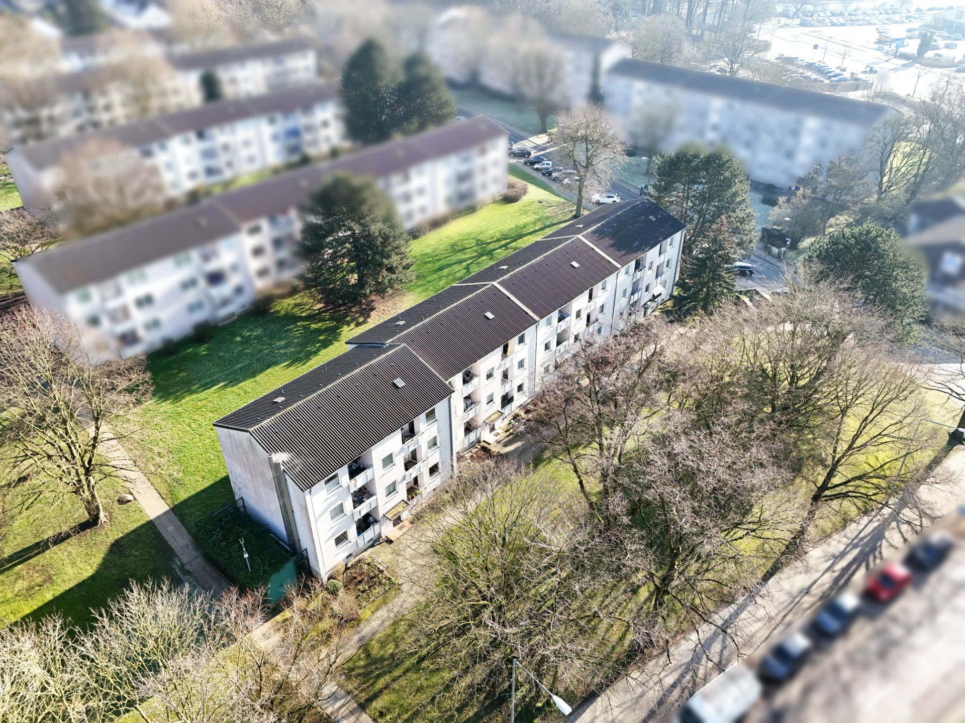 Mehrfamilienhaus mit mehreren Wohnungen, umgeben von Bäumen und Grünflächen.