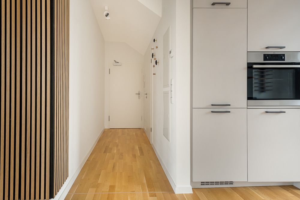 Heller Flur mit Holzboden, weißer Tür und Einbauschränken.