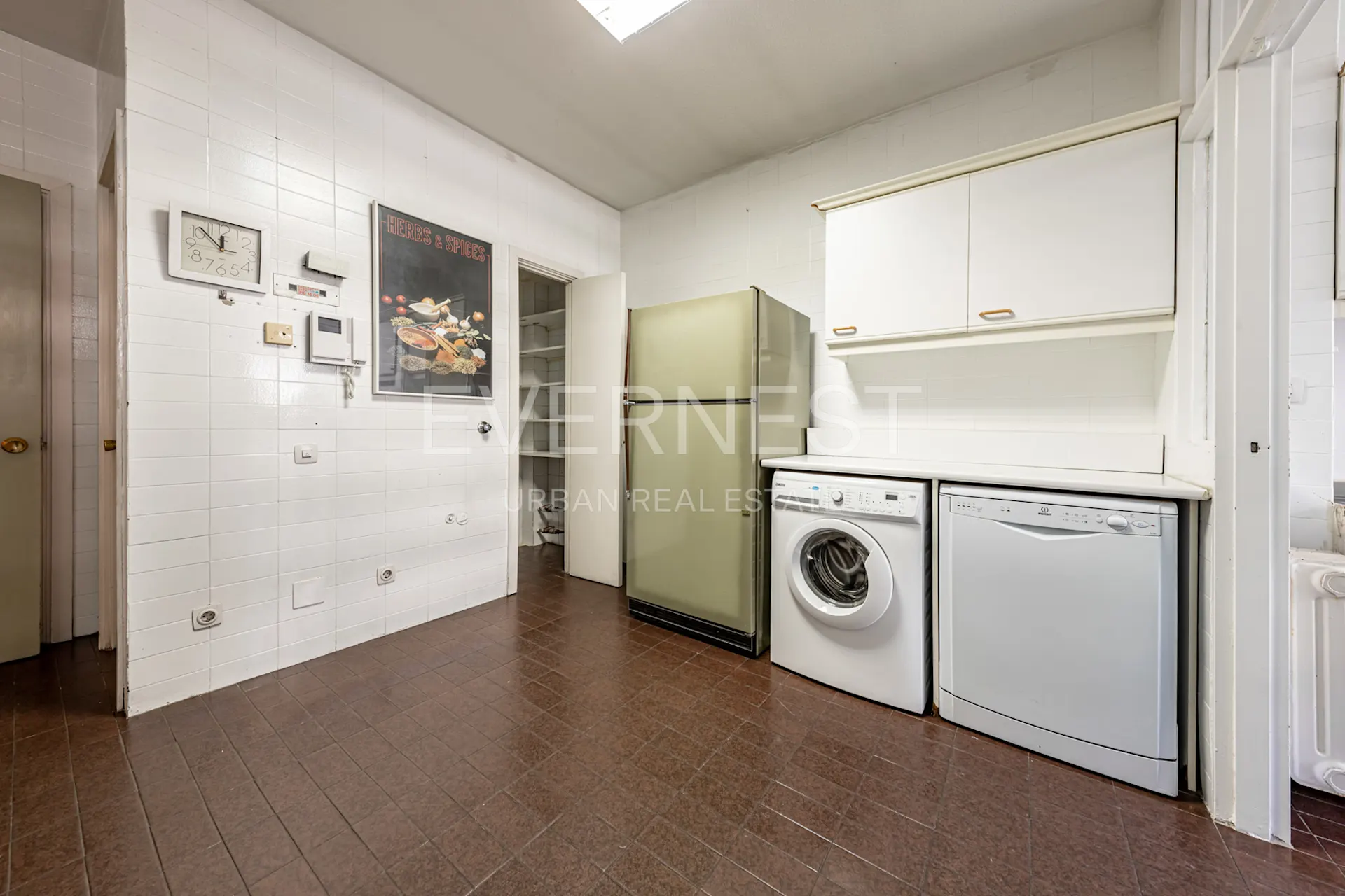 Küche mit Kühlschrank, Waschmaschine, Geschirrspüler und weißen Wandschränken.