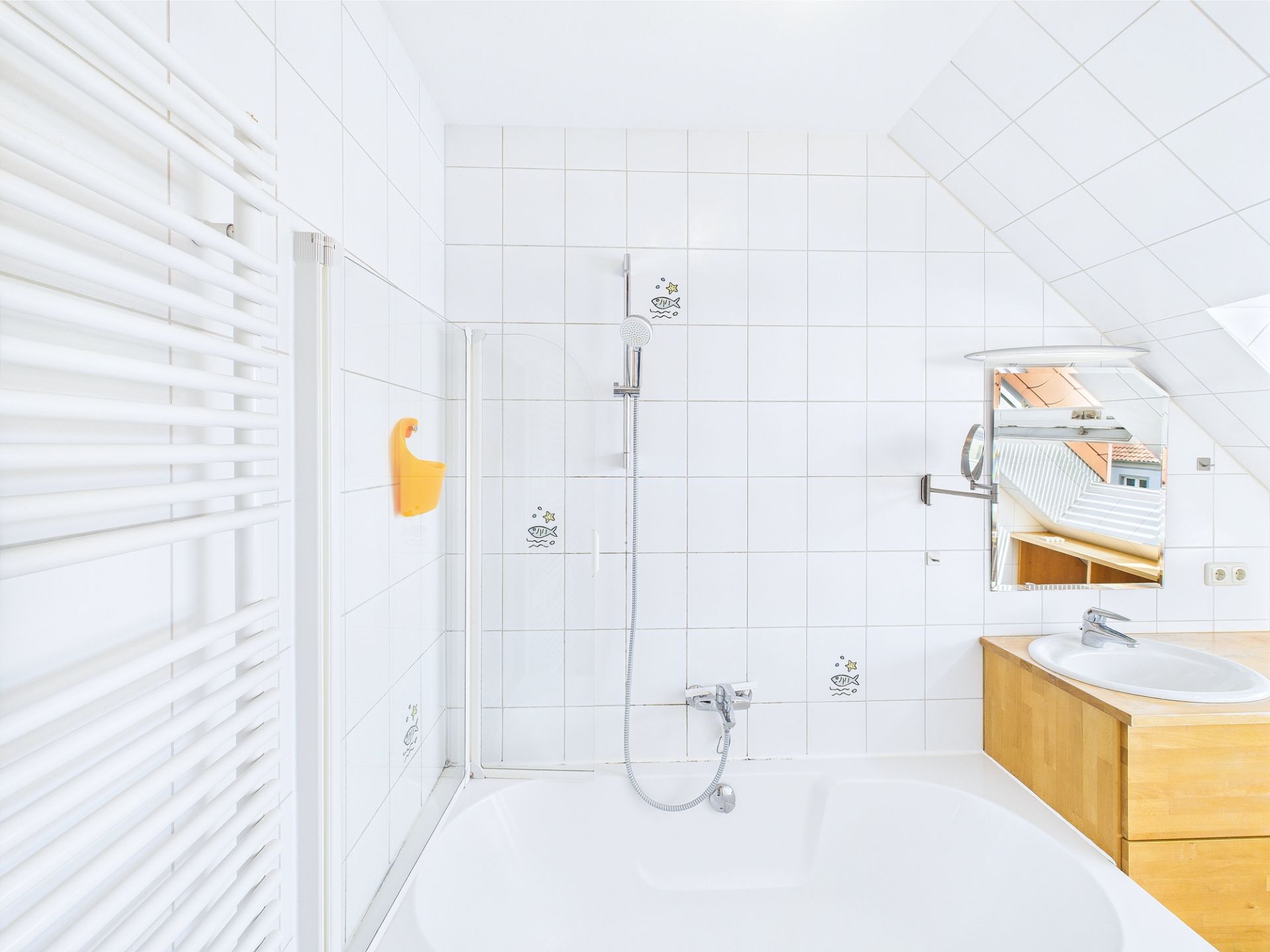 Modernes Badezimmer mit Badewanne, Dusche, Waschbecken und Spiegel unter einer Dachschräge.