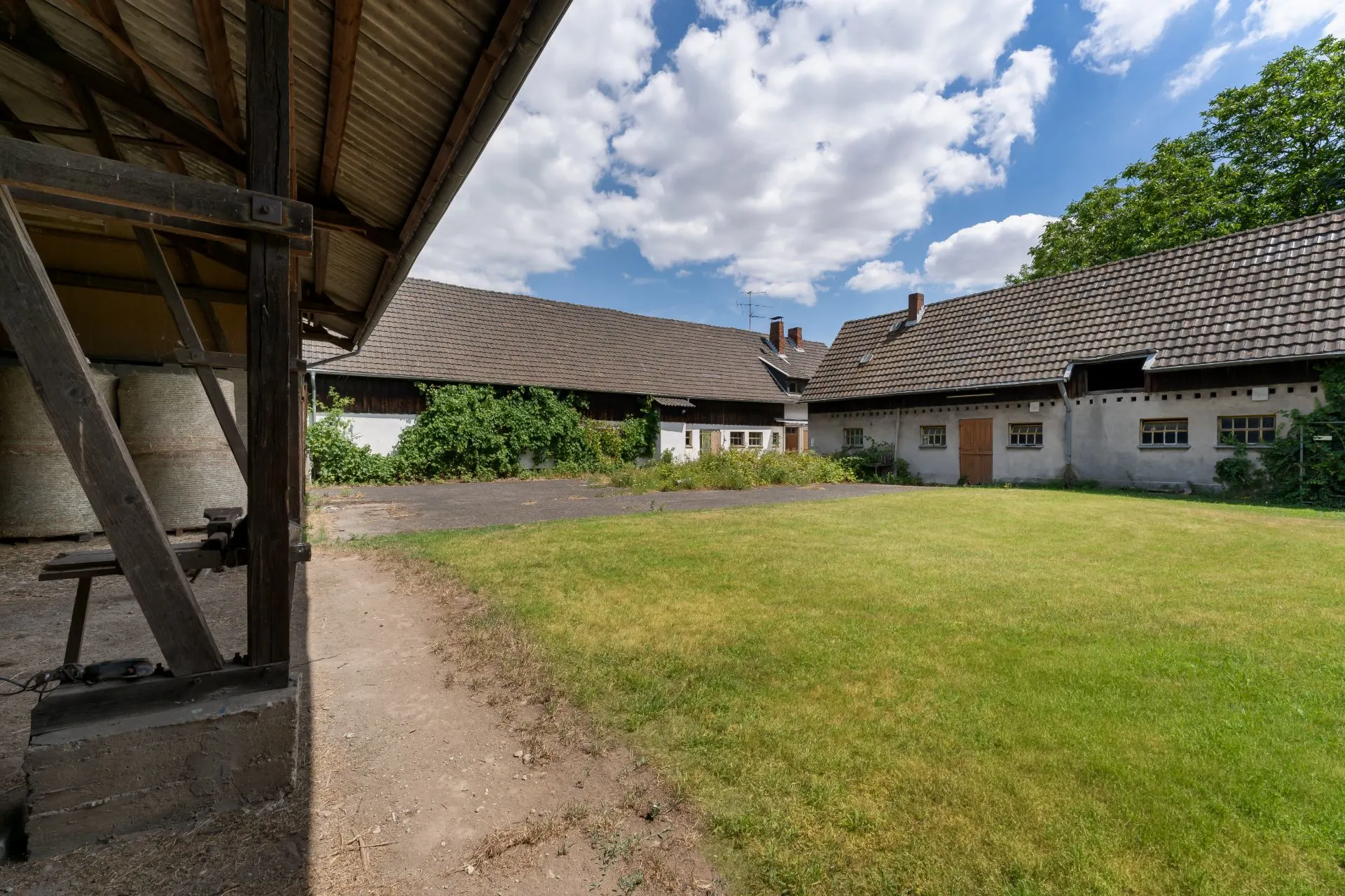 Innenhof mit Rasenfläche, umgeben von Gebäuden mit Satteldächern und begrünten Fassaden.