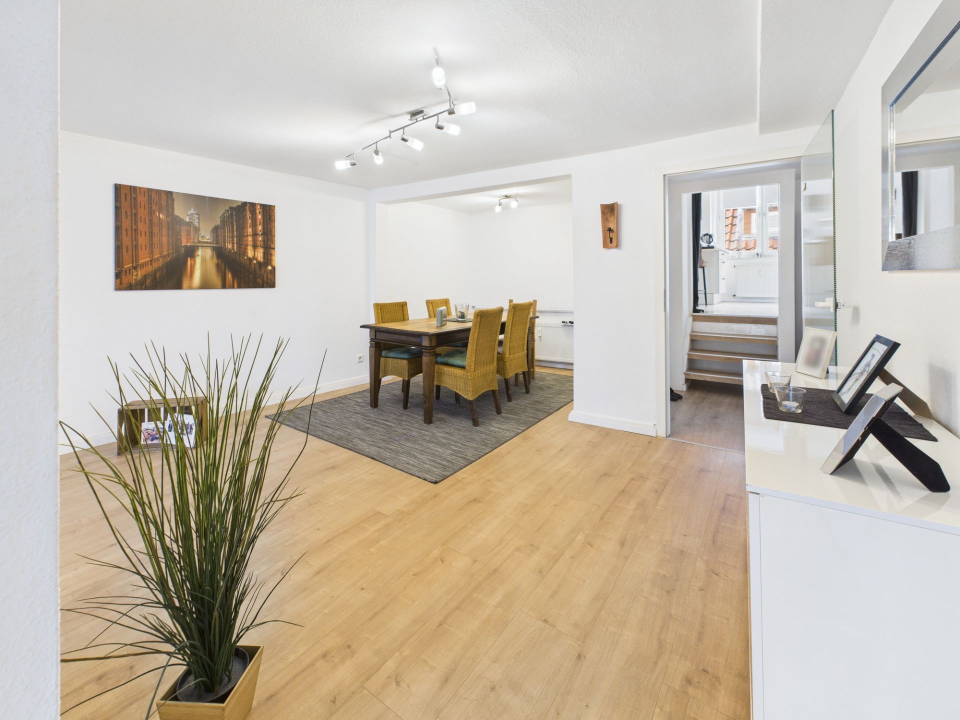 Essbereich mit Tisch, sechs Stühlen, heller Holzboden und moderner Beleuchtung.