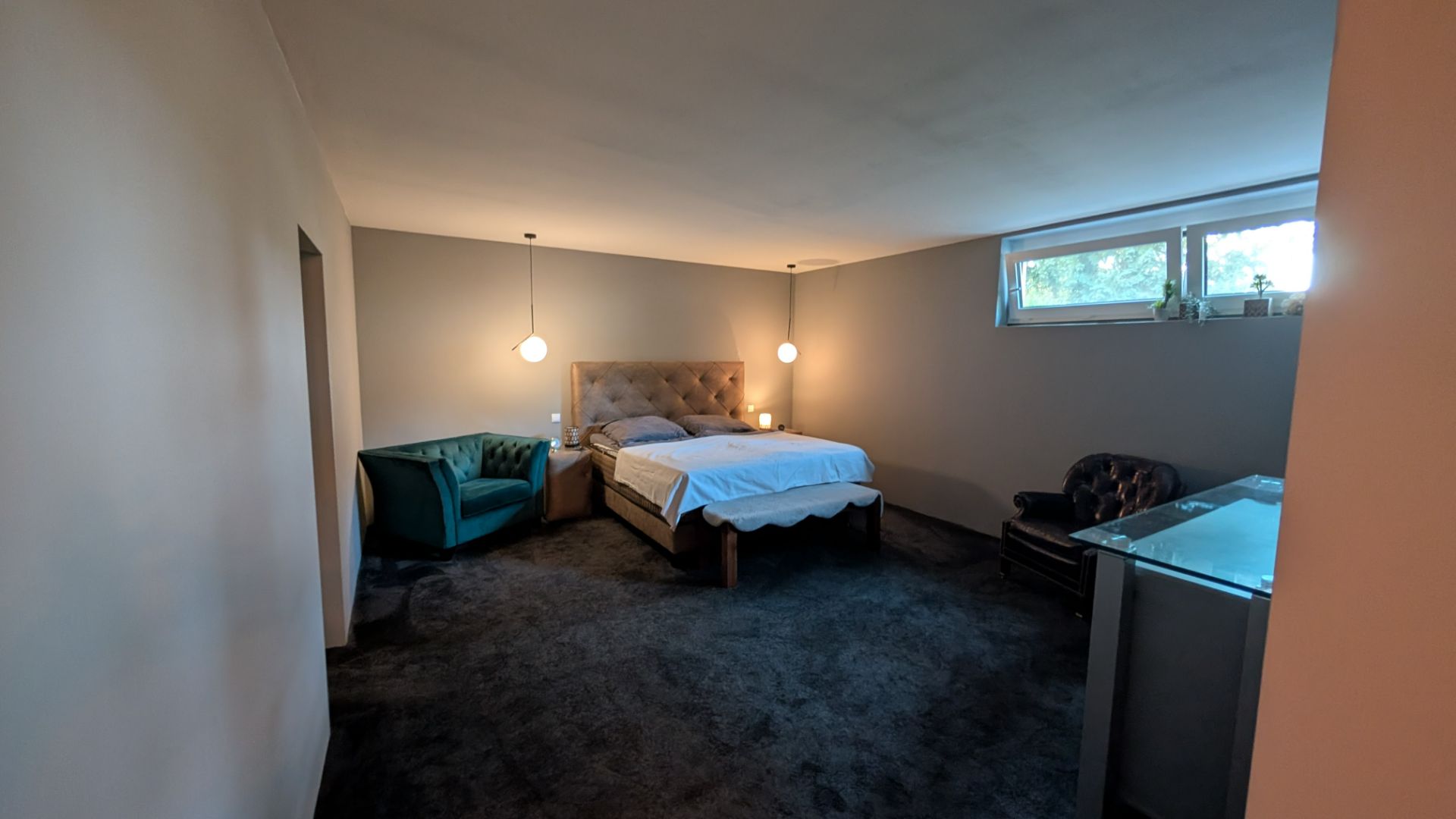 Großes Schlafzimmer mit Doppelbett, zwei Sesseln, Schreibtisch und Fenster.