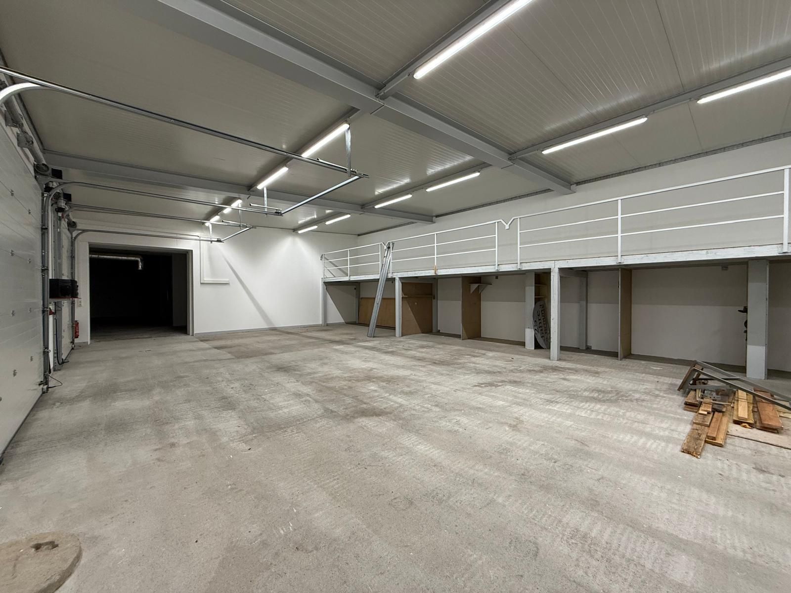 Leere große Garage mit Betonboden, weißer Wand und Metallgeländer auf einer Empore.