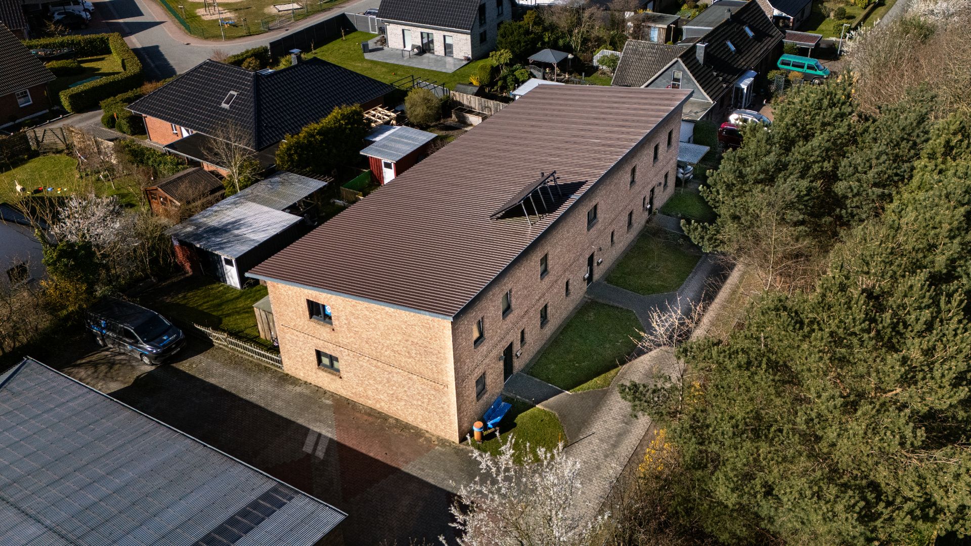 Langes, zweistöckiges Wohnhaus aus Backstein mit Satteldach und umliegendem Garten, aus der Vogelperspektive.