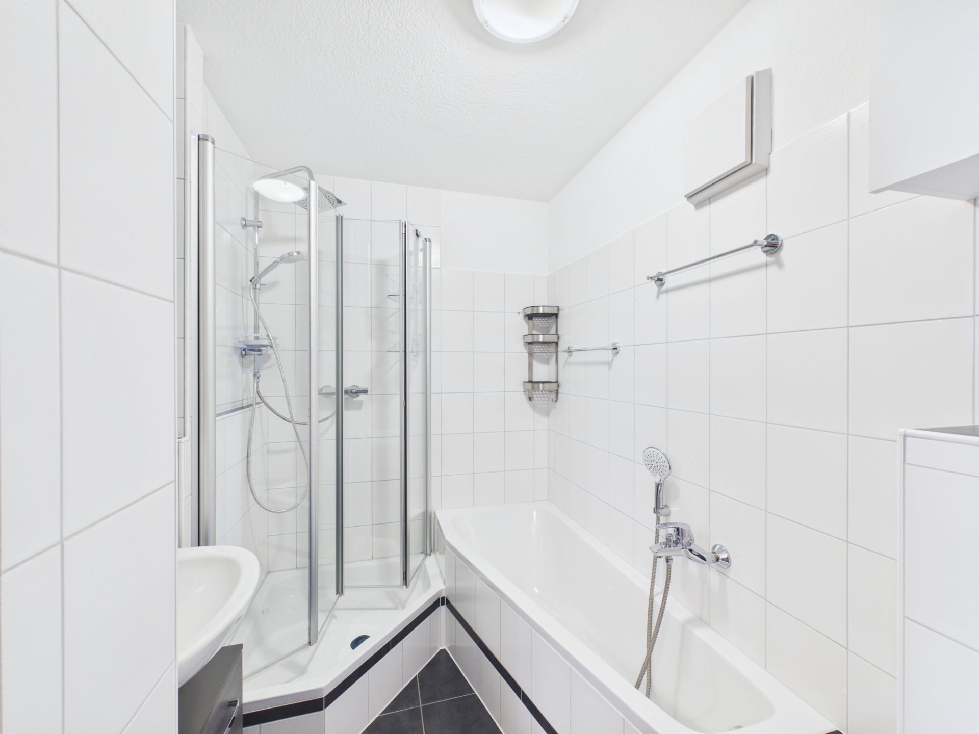 Helles Badezimmer mit Dusche, Badewanne und weißen Fliesen.