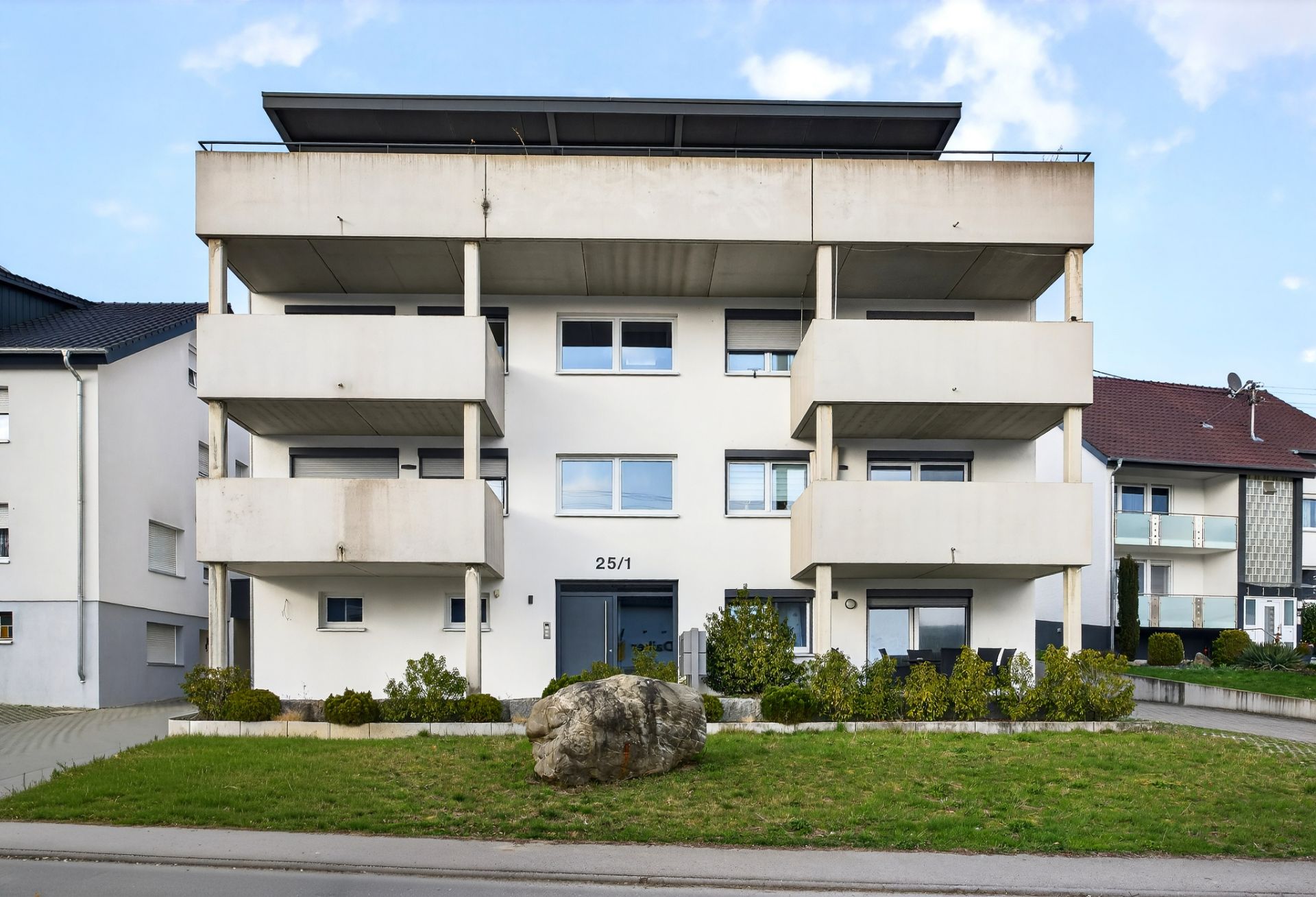 Modernes Mehrfamilienhaus mit Balkonen und gepflegtem Vorgarten.